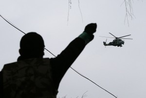 A man gestures while pro-Russian protesters gather at the police headquarters, while a military helicopter flies above, in Slaviansk