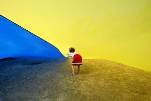 A girl walks under a giant Ukrainian national flag, held by people celebrating the Day of the State Flag, in Kiev